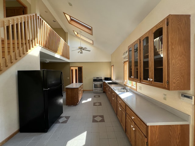 320 Spring Rd, Augusta, ME 04330 - kitchen featuring freestanding refrigerator, brown cabinets, stainless steel gas stove, a kitchen island, and a skylight