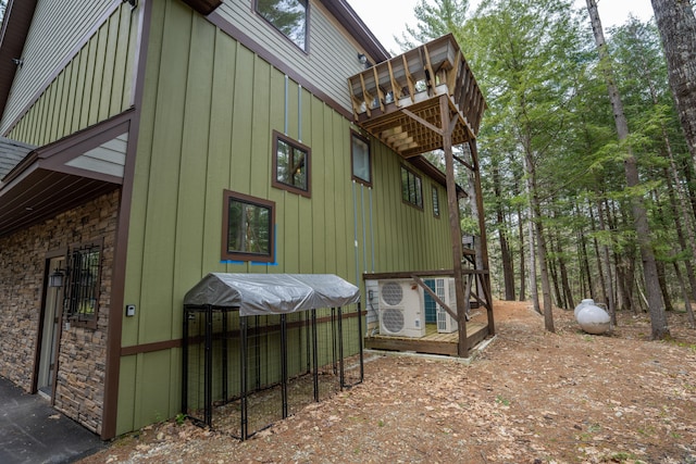 106 Webb River Dr, Dixfield, ME 04224 - view of home's exterior featuring board and batten siding, a balcony, stone siding, and ac unit