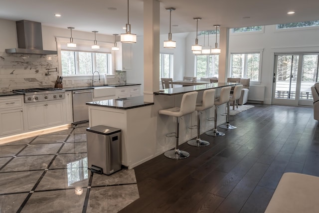 106 Webb River Dr, Dixfield, ME 04224 - kitchen featuring wall chimney range hood, appliances with stainless steel finishes, dark countertops, dark wood-style flooring, and tasteful backsplash