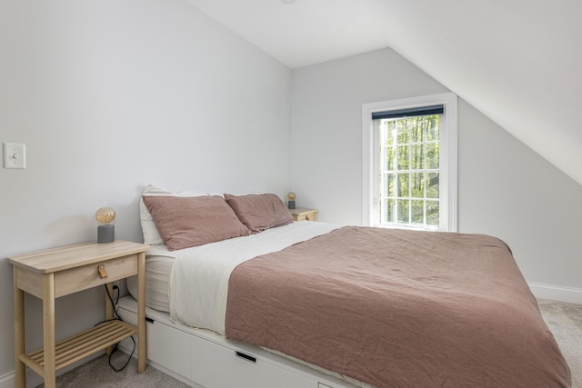 bedroom with light carpet, lofted ceiling, and baseboards