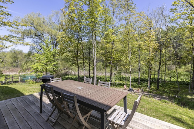 wooden deck featuring outdoor dining area and a lawn