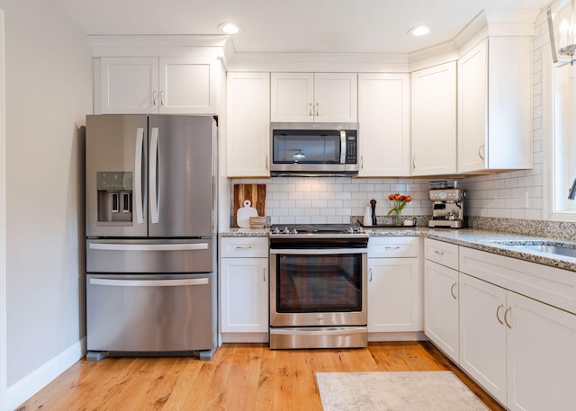 22 Lilac Ln, Gorham, ME 04038 - kitchen with appliances with stainless steel finishes, a sink, white cabinets, decorative backsplash, and light wood-style floors