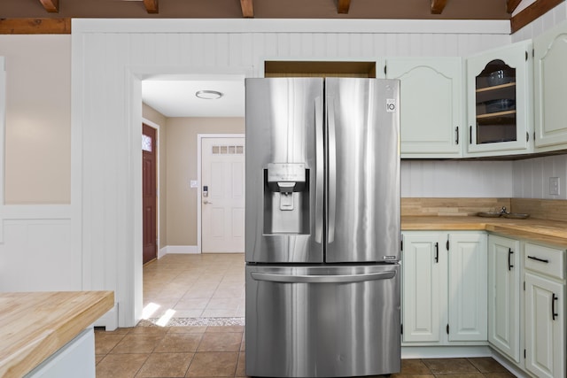 591 Eight Rod Rd, Augusta, ME 04330 - kitchen with stainless steel refrigerator with ice dispenser, butcher block counters, light tile patterned floors, and glass insert cabinets