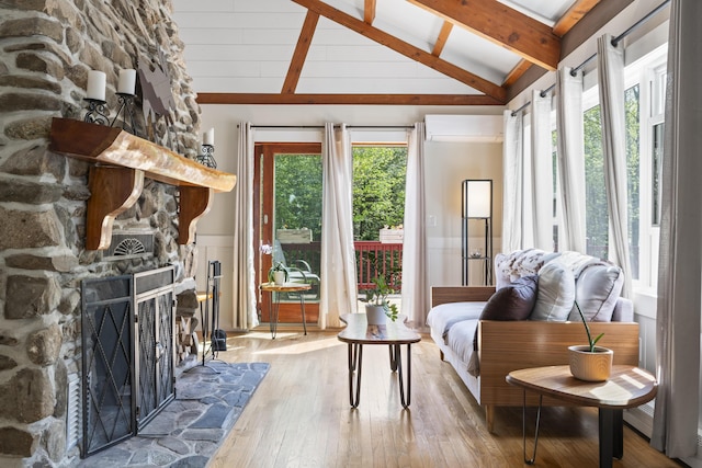 591 Eight Rod Rd, Augusta, ME 04330 - living room with beam ceiling, hardwood / wood-style floors, a stone fireplace, a wall mounted air conditioner, and high vaulted ceiling