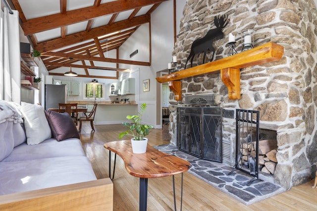 591 Eight Rod Rd, Augusta, ME 04330 - living area featuring wood finished floors, high vaulted ceiling, a stone fireplace, and beam ceiling