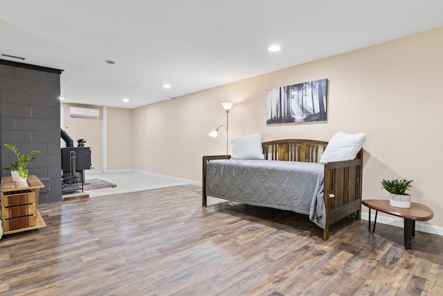 591 Eight Rod Rd, Augusta, ME 04330 - bedroom featuring an AC wall unit, wood finished floors, a wood stove, baseboards, and recessed lighting