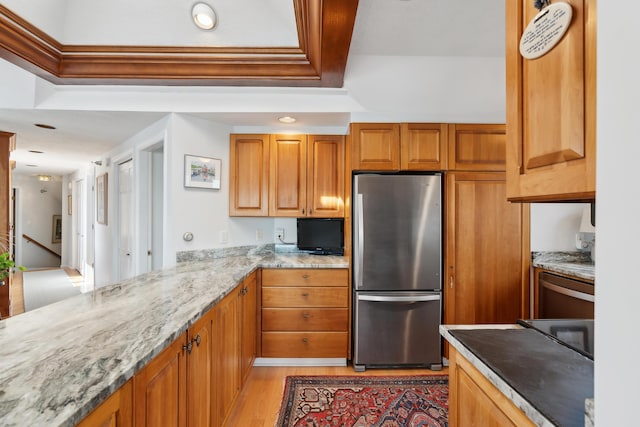 15 Christensen Ln Unit A1, Kennebunk, ME 04043 - kitchen featuring freestanding refrigerator, light wood finished floors, light stone countertops, and brown cabinets