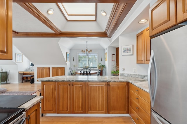 15 Christensen Ln Unit A1, Kennebunk, ME 04043 - kitchen featuring appliances with stainless steel finishes, light wood finished floors, brown cabinets, a chandelier, and vaulted ceiling