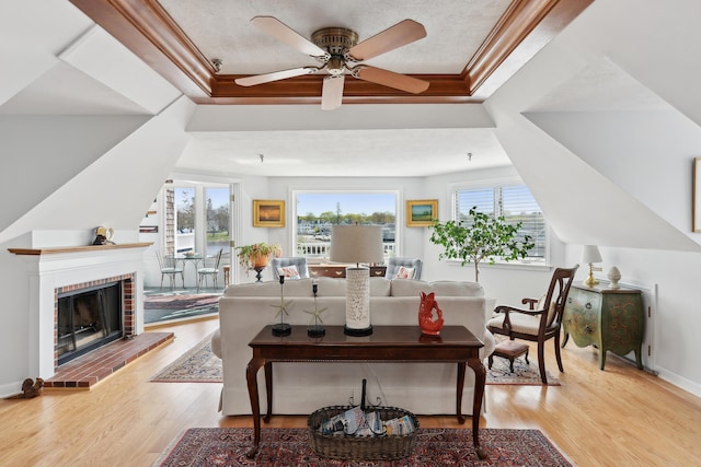 15 Christensen Ln Unit A1, Kennebunk, ME 04043 - living area with light wood-type flooring, crown molding, ceiling fan, a fireplace, and a raised ceiling