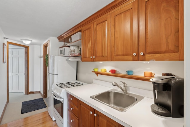 15 Christensen Ln Unit A1, Kennebunk, ME 04043 - kitchen featuring white appliances, a sink, light countertops, brown cabinets, and baseboards