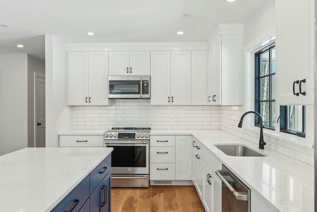 11 Acorn Ave, Kennebunkport, ME 04046 - kitchen featuring appliances with stainless steel finishes, a sink, white cabinets, light stone counters, and blue cabinetry