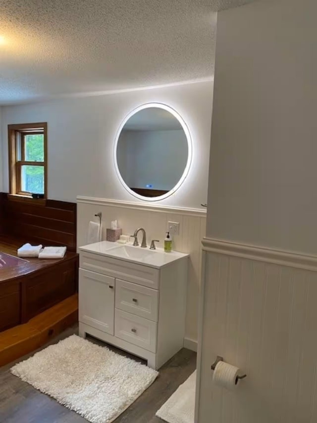 597 Sweden Rd, Bridgton, ME 04009 - bathroom featuring a textured ceiling, wood finished floors, wainscoting, and vanity