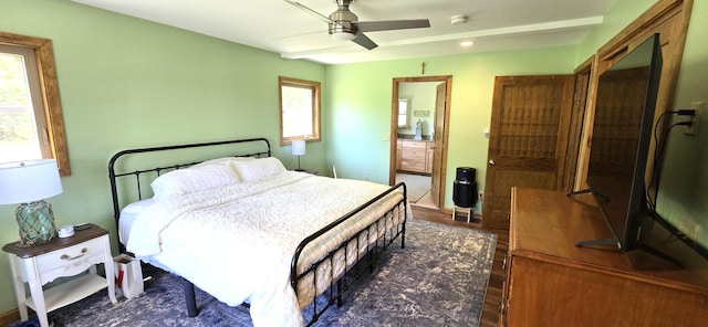 bedroom with multiple windows, wood finished floors, ensuite bath, and a ceiling fan