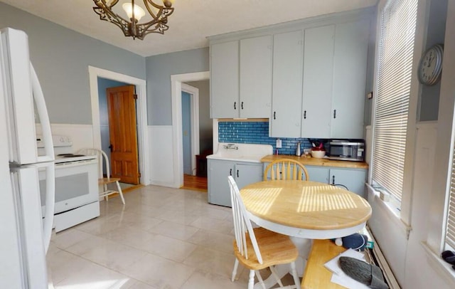 kitchen featuring white appliances, a chandelier, light countertops, and tasteful backsplash