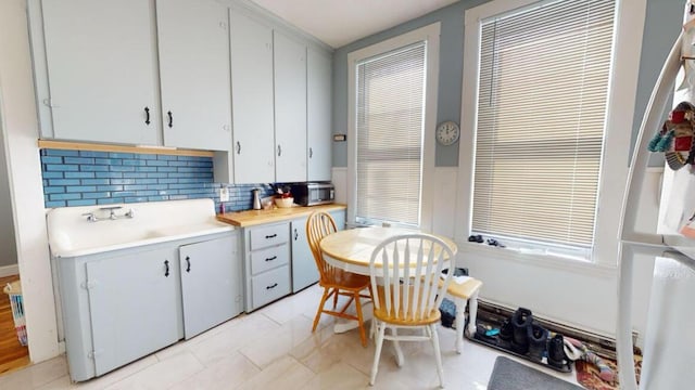 kitchen featuring light countertops, backsplash, a sink, and white cabinets