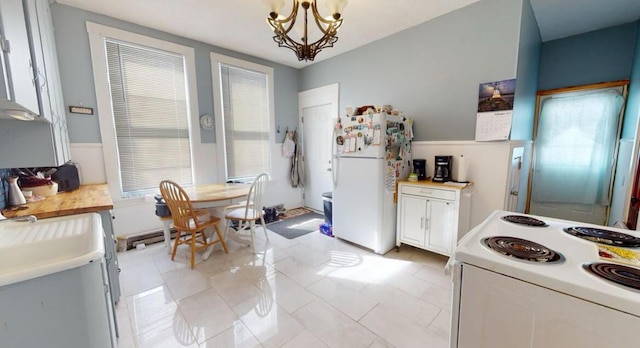 kitchen featuring white appliances, light countertops, a chandelier, light tile patterned flooring, and pendant lighting