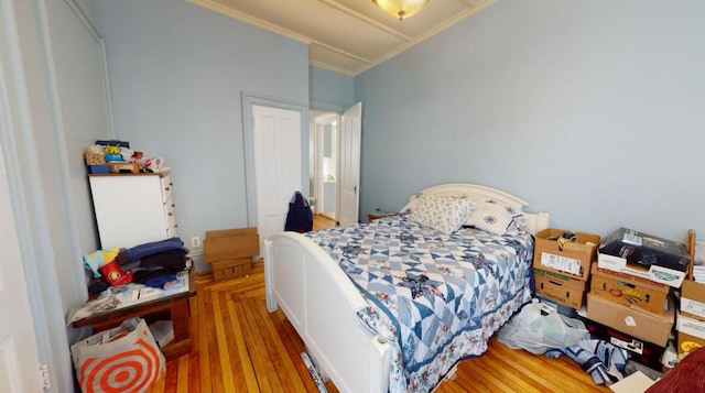 bedroom with ornamental molding and wood finished floors
