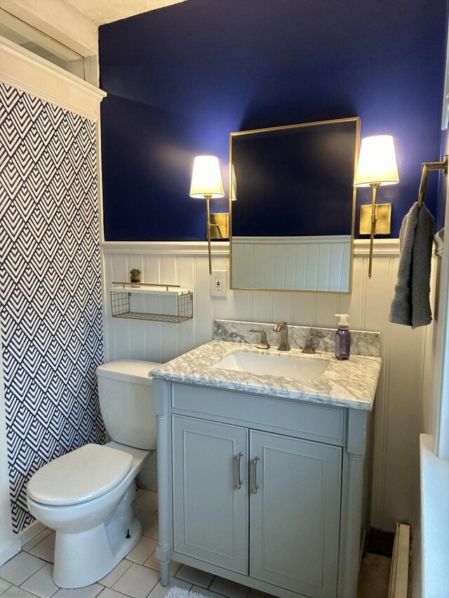 full bath featuring wainscoting, toilet, vanity, tile patterned floors, and a shower with curtain