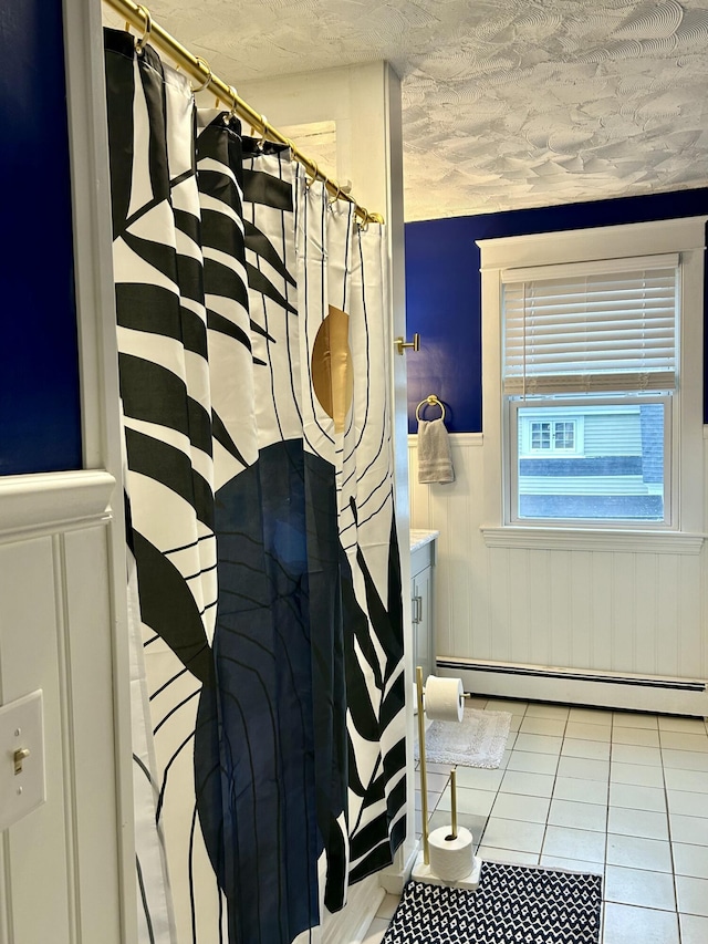bathroom with a baseboard radiator, tile patterned flooring, wainscoting, a textured ceiling, and a shower with curtain