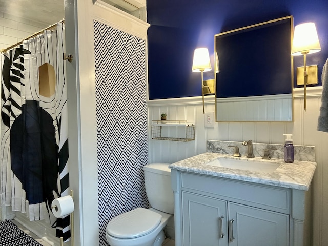 full bath with toilet, vanity, a wainscoted wall, and a shower with shower curtain