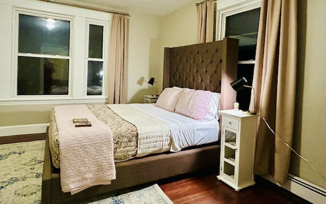 bedroom with dark wood finished floors, a baseboard radiator, and baseboards