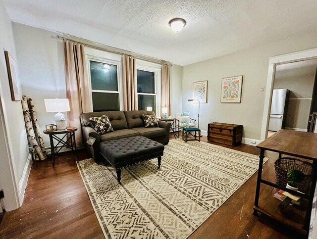living room featuring dark wood finished floors, a textured ceiling, and baseboards
