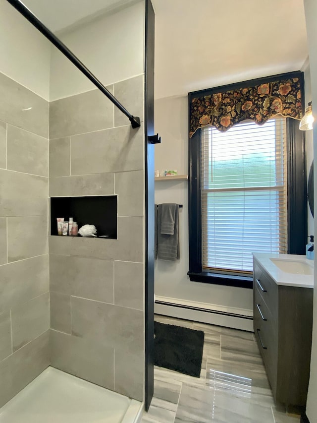bathroom with a baseboard radiator, tiled shower, and vanity