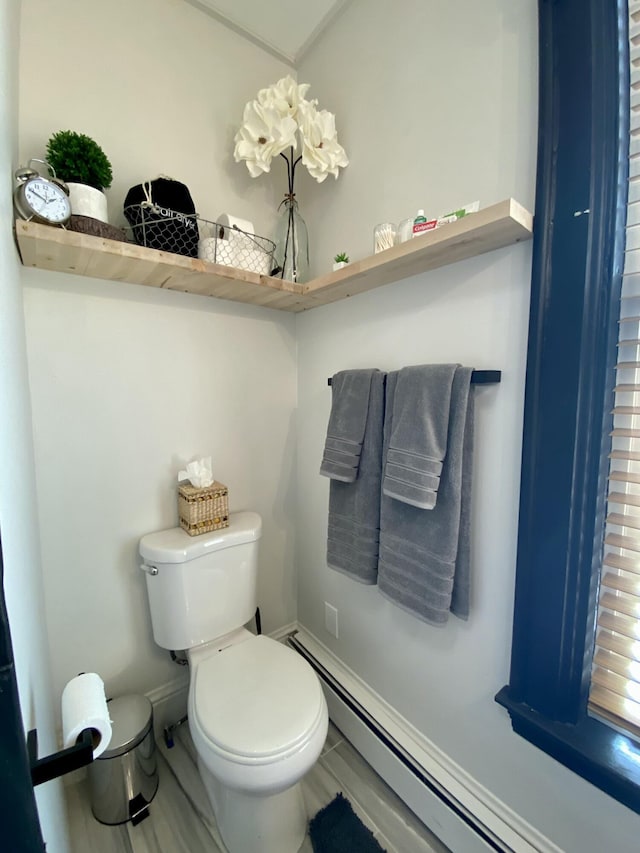 bathroom with a baseboard heating unit, toilet, and baseboards
