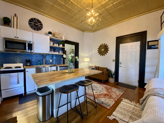kitchen with wood counters, white range with electric stovetop, stainless steel microwave, an ornate ceiling, and white cabinetry