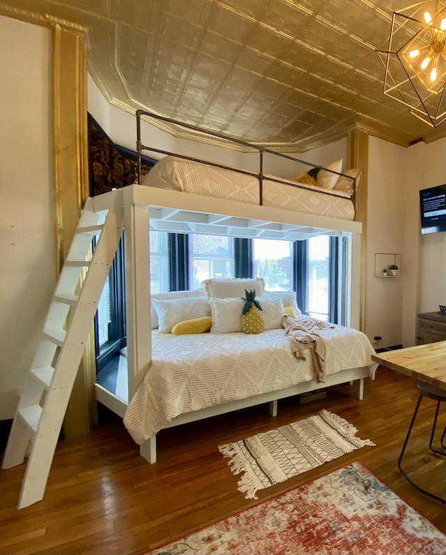 bedroom featuring an ornate ceiling, a chandelier, and wood finished floors