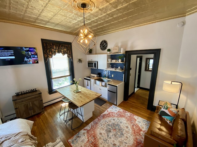 dining room featuring an ornate ceiling, a chandelier, a baseboard radiator, dark wood-style floors, and ornamental molding