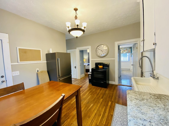 dining room featuring dark wood finished floors, baseboard heating, a chandelier, baseboards, and a textured ceiling