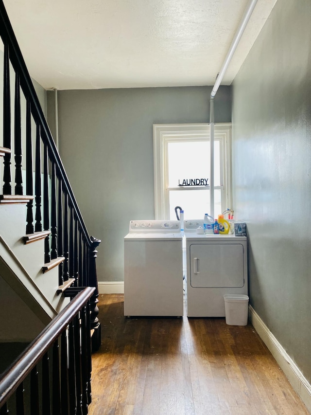 clothes washing area featuring washer and dryer, hardwood / wood-style flooring, and baseboards