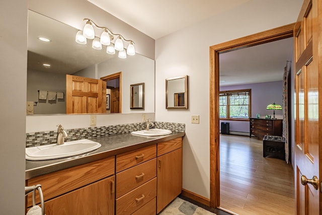 1 Mayflower Way, Norway, ME 04268 - full bathroom featuring double vanity, baseboards, backsplash, a baseboard heating unit, and wood finished floors