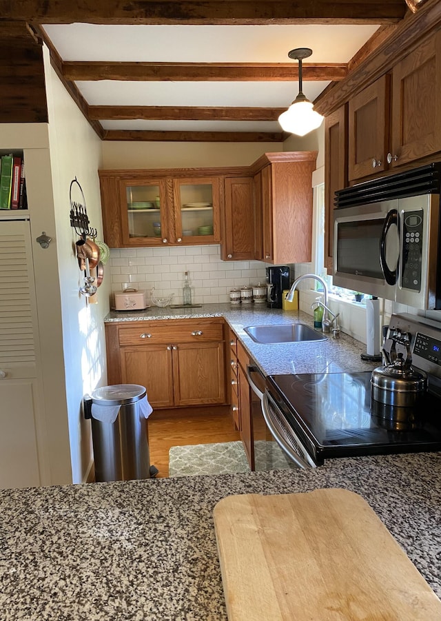 12 Old Rte 1, Searsport, ME 04974 - kitchen featuring appliances with stainless steel finishes, a sink, brown cabinets, beamed ceiling, and tasteful backsplash