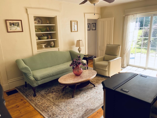 12 Old Rte 1, Searsport, ME 04974 - living room featuring a ceiling fan, light wood finished floors, built in shelves, and crown molding