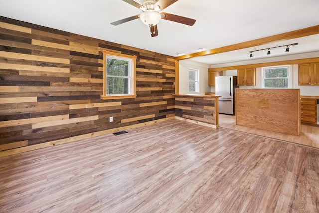227 Forest Ave, Orono, ME 04473 - unfurnished living room featuring light wood-type flooring, a ceiling fan, wood walls, and track lighting