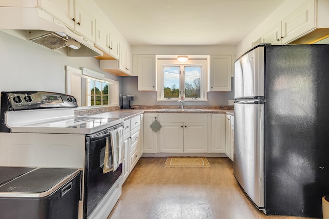 kitchen with freestanding refrigerator, white range with electric cooktop, under cabinet range hood, a sink, and white cabinetry