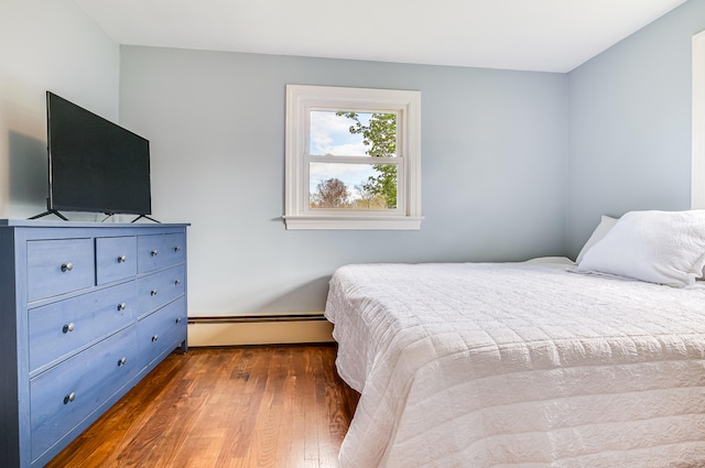 bedroom featuring a baseboard heating unit, dark wood-style flooring, and baseboards