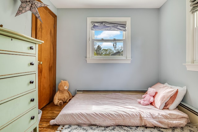 bedroom with dark wood-style flooring and a baseboard radiator