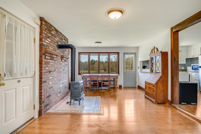 sitting room featuring a wood stove, wood finished floors, brick wall, and baseboards