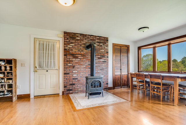dining space featuring wood finished floors, a wood stove, and baseboards