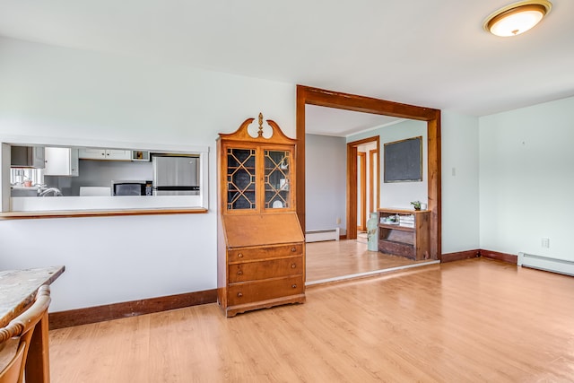 dining space with baseboard heating, wood finished floors, and baseboards