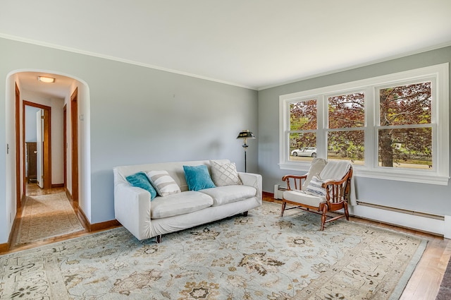 living area featuring arched walkways, ornamental molding, wood finished floors, and baseboards