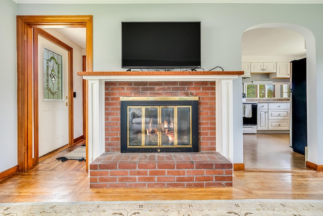 detailed view of a fireplace, wood finished floors, baseboards, and stove