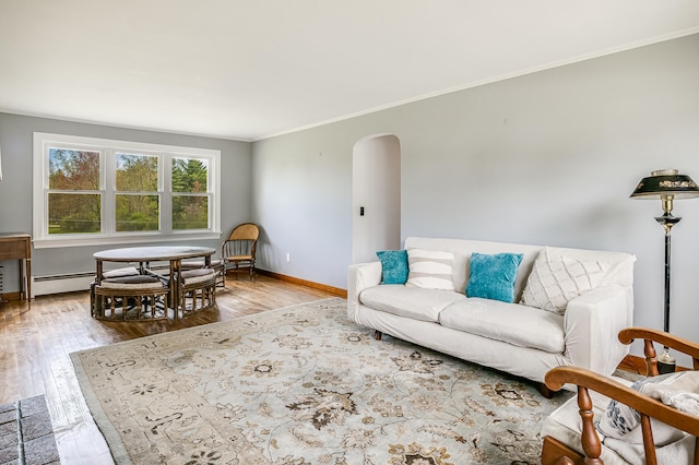 living room featuring arched walkways, light wood-type flooring, crown molding, and baseboards