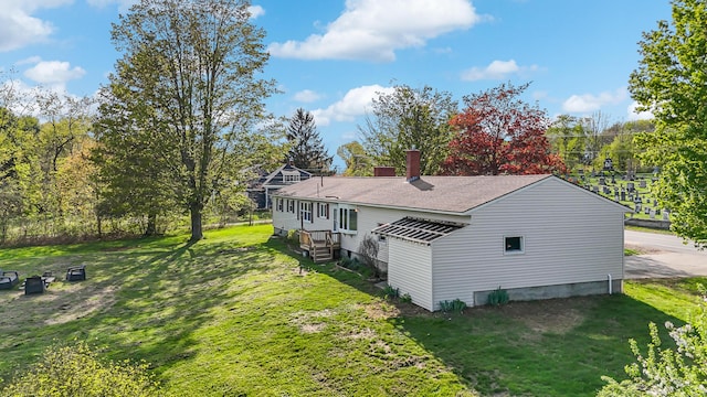 view of property exterior with a yard, a shingled roof, and a chimney