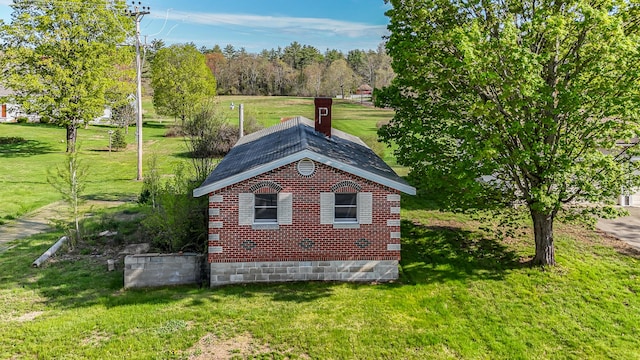 view of side of home featuring a lawn, a chimney, and brick siding