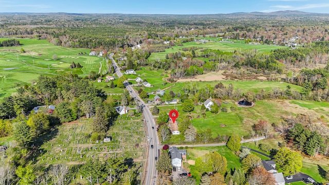 aerial view of property and surrounding area featuring a golf course and a heavily wooded area