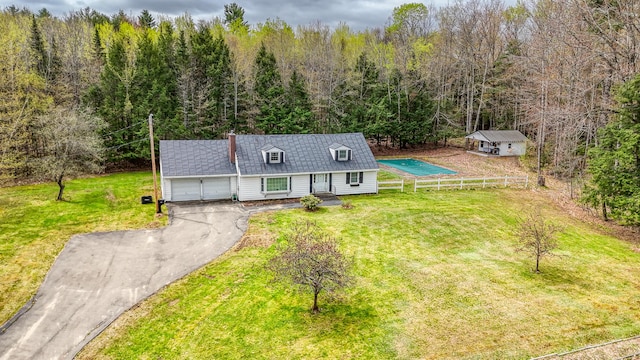 view of front facade featuring an attached garage, asphalt driveway, a view of trees, and metal roof